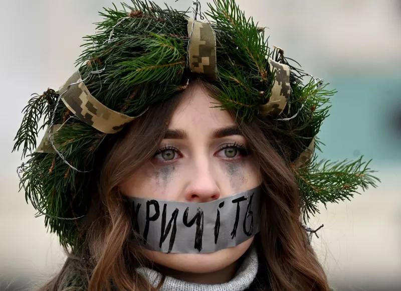 Russia-Ukraine war day of 1040.... A protester wearing a Christmas wreath has her mouth taped with a slogan reading "Shout" during a rally calling for the exchange of Ukrainian